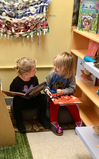 two kids sitting down and holding picture books while talking to each other wellfleet ma